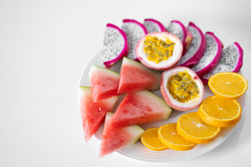 White plate of sliced fruit. Fresh fruits and vitamins. Still life colored summer fruits.