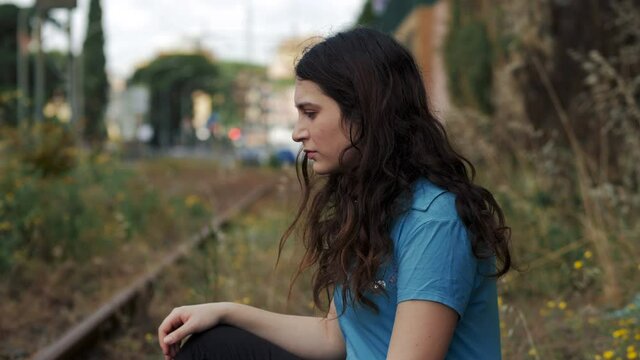young pensive woman turning her head and looking serious at camera - outdoors