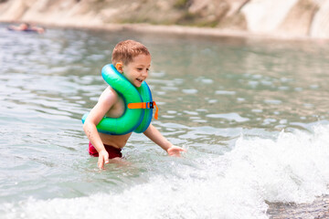 Fototapeta premium a boy in a life jacket is standing on the sea