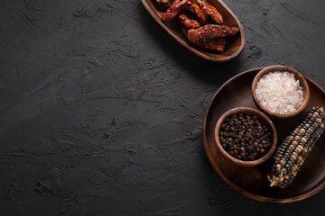 Dried tomatoes concept with wooden presentation board on black stone floor ( with copy space )