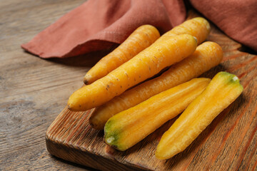 Raw yellow carrots on wooden board, closeup