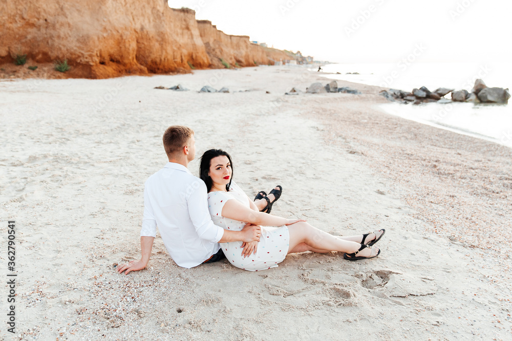 Wall mural loving couple in white clothes during a honeymoon at sea walk on the sand at a photoshoot love story