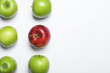 Red apple among green ones on white background, top view