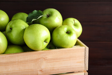 Juicy green apples in crate on wooden background, closeup