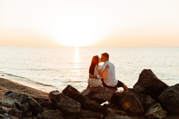 Fototapeta premium Loving couple in white clothes during a honeymoon at sea walk on the sand at a photoshoot Love Story, ocean coast, beach