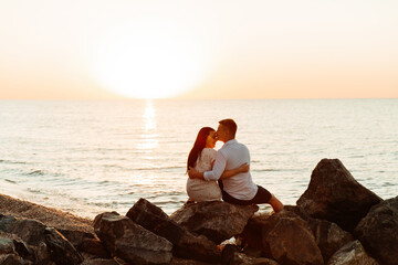 Loving couple in white clothes during a honeymoon at sea walk on the sand at a photoshoot Love Story, ocean coast, beach