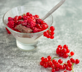 Ice cream in a glass bowl and red summer berries currants and raspberries on a light background; Summer still life, close-up, refreshing treat
