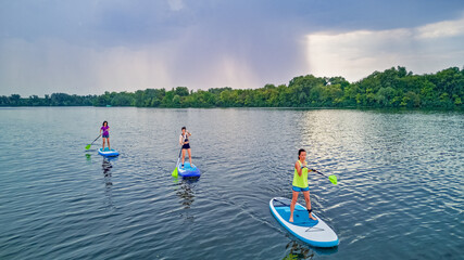 Active family on SUPs, standing up paddleboards, in river water, summer family sport, aerial top...