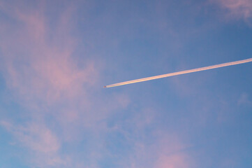 Trace in an airplane in the sky against the sunset pink sky