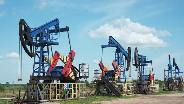 Oil derricks against cloudy sky