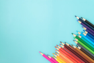 Colored pencils laid out on a turquoise background. School office. Colored pencils laid out in the corner