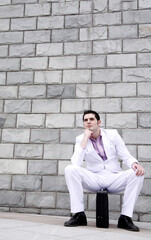 Obraz premium Businessman thinking while sitting on briefcase