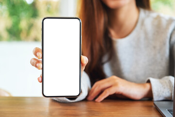 Mockup image of a beautiful woman holding and showing a mobile phone with blank white screen