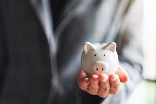 Closeup image of a businesswoman holding a piggy bank for saving money and financial concept