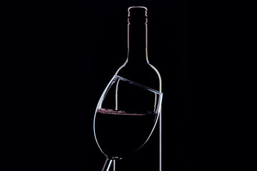 A glass of red wine and bottle  on dark background