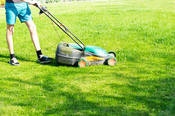 young man mows the lawn.