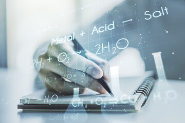 Double exposure of creative chemistry concept with man hand writing in notebook on background, research and development concept