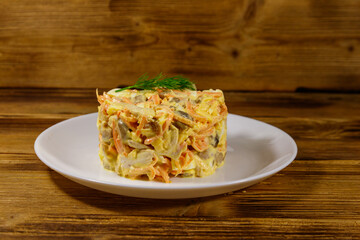 Tasty salad with chicken breast, roasted mushrooms, carrots, grated cheese, eggs and mayonnaise on wooden table