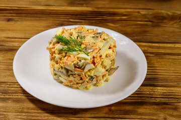 Tasty salad with chicken breast, roasted mushrooms, carrots, grated cheese, eggs and mayonnaise on wooden table