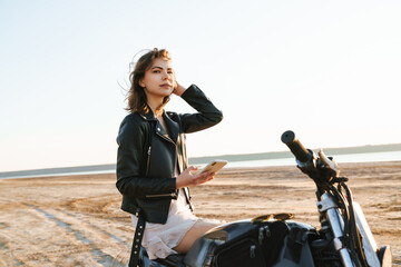 Beautiful young girl wearing leather jacket sitting on a motorbike