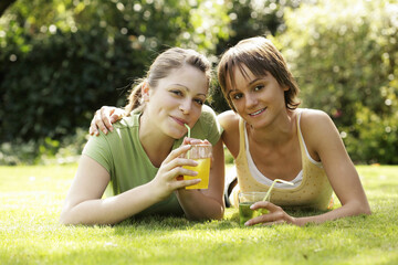 Teenage girls lying forward on the field enjoying their drinks