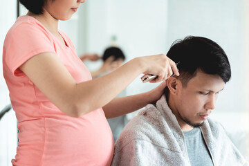 Obraz na płótnie Canvas Young Pregnant Woman cutting husband hair with clipper at home