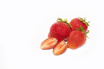 several strawberries next to a sliced strawberry in two pieces isolated on white background