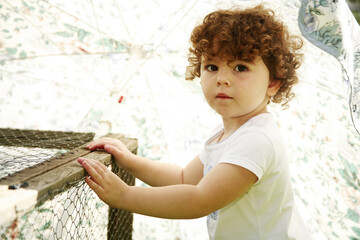 Cute little young girl standing beside a cage