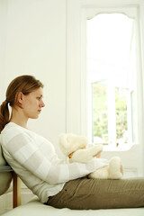 Woman hugging teddy bear while daydreaming