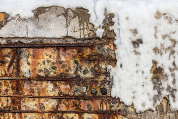 Background old cracked wall of a building with a metal armature covered with ice