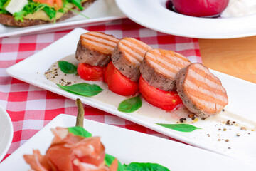 Delicious cut beef steak served on a white plate over red plaid tablecloth. Italian concept, Italian cuisine. Flat lay.