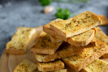 Wooden cutting board with delicious homemade garlic bread on the cement floor