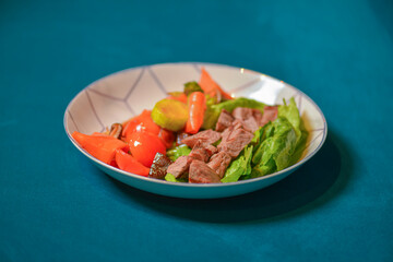 Roasted meat and vegetables salad with tomatoes and brocolli served in a white bowl. Healthy dinner.