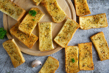 Wooden cutting board with delicious homemade garlic bread on the cement floor