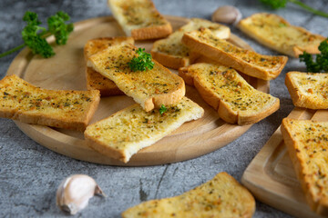 Wooden cutting board with delicious homemade garlic bread on the cement floor