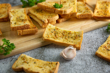 Wooden cutting board with delicious homemade garlic bread on the cement floor