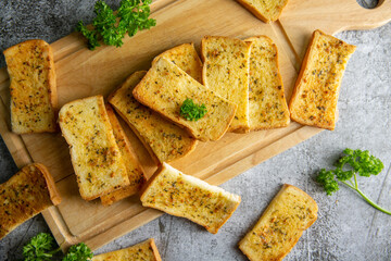 Wooden cutting board with delicious homemade garlic bread on the cement floor