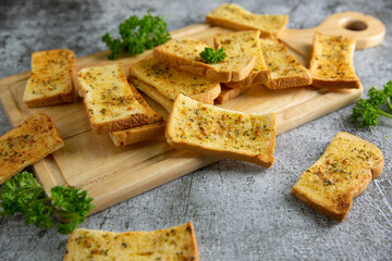 Wooden cutting board with delicious homemade garlic bread on the cement floor