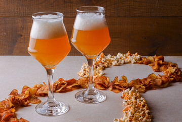 Two glass of beer and beer snacks over white background. Potato chips and popcorn shaped like an 8.