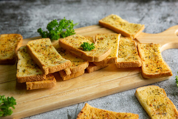 Wooden cutting board with delicious homemade garlic bread on the cement floor