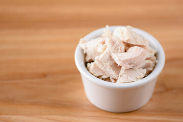 Bowl of boiled chicken on wooden background. Snack, appetizer. Copy space banner. Pizza ingredient