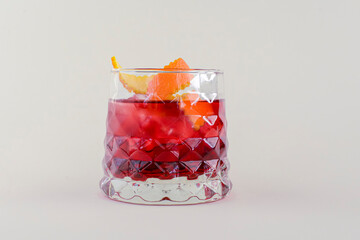 Cold summer alcohol cocktail with ice and orange in a small glass isolated on white background.