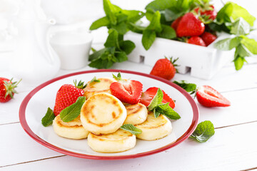 Fototapeta na wymiar Cheese pancakes, fritters or syrniki with fresh strawberry and yogurt. Healthy and tasty breakfast