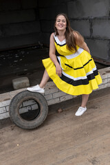Fototapeta na wymiar young beautiful girl in a yellow dress on a construction site