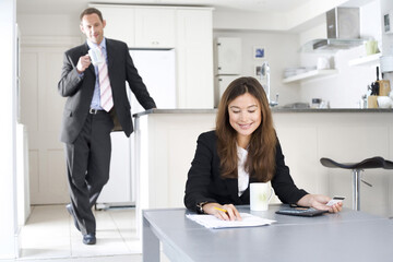 Businesswoman working out some calculations with businessman looking on