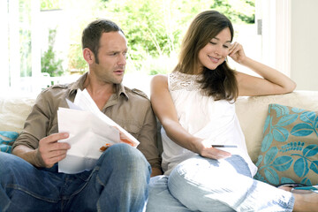 Man looking at woman talking on mobile phone, holding a credit card