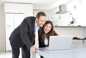Businesswoman working on laptop with businessman looking on
