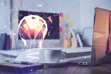 Computer on desktop in office with bulb icon hologram. Double exposure. Concept of idea.