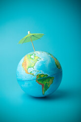 Fototapeta premium Global warming and climate change on earth concept. Earth globe on a blue background with an umbrella. Protecting the atmosphere from ultraviolet radiation and ozone holes