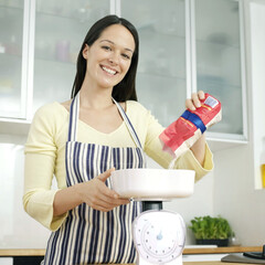 Woman pouring flour onto weight scale